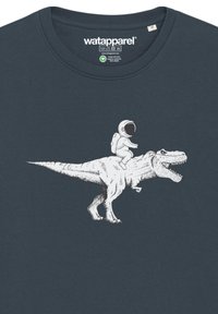T-shirt marine avec un imprimé graphique d'un dinosaure avec un astronaute à dos, rendu en blanc, mettant en avant des textures et contours détaillés.