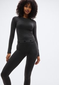 Γκρι θερμικό μακρυμάνικο τοπ και κολάν από μαλακό ύφασμα, με εφαρμοστή σχεδίαση και διακριτική λεπτομέρεια λογοτύπου στη μέση.