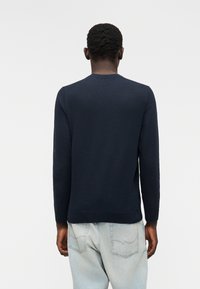 Μπλε σκούρο, πουλόβερ με μακριά μανίκια από απαλό πλεκτό ύφασμα, με στρογγυλή λαιμόκοψη και ριμπ μανσέτες, συνδυασμένο με ανοιχτό μπλε τζιν.