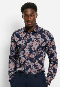 Navy-blaues Blusenshirt mit floralem Muster, das zarte rosa und weiße Blumen mit grünen Akzenten zeigt; lange Ärmel und figurbetonter Schnitt. Glattes Baumwollmaterial.