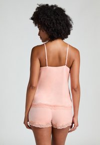 Set de top și pantaloni scurți din satin roz, cu dantelă la margini. Topul are bretele subțiri și un decolteu drept. Textura moale și designul ușor.