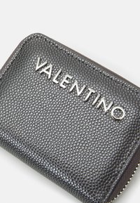 Carteira de couro preto texturizado com a marca "VALENTINO" em prateado. Apresenta um fecho de zíper e uma forma retangular compacta.
