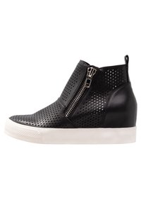 Botas de tobillo de cuero negro perforado con cremallera lateral y suela de goma blanca. Presentan un diseño elegante y una forma de punta redondeada.