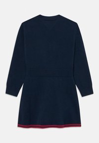 Marinblå stickad klänning med långa ärmar och ribbad midja; har en rödrandig fåll längst ner.