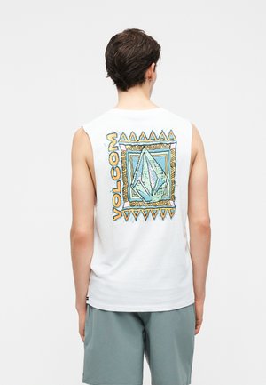 Άνδρας που φοράει λευκό αμάνικο μπλουζάκι Volcom με πολύχρωμο γεωμετρικό λογότυπο στην πλάτη και ανοικτό μπλε σορτσάκι, στραμμένος προς τα πίσω με λευκό φόντο.