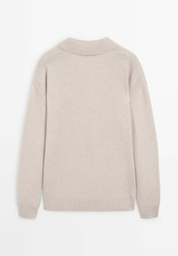 Pull en maille beige clair avec col et poignets côtelés, présentant une coupe décontractée et des coutures aux épaules pour ajouter de la texture.