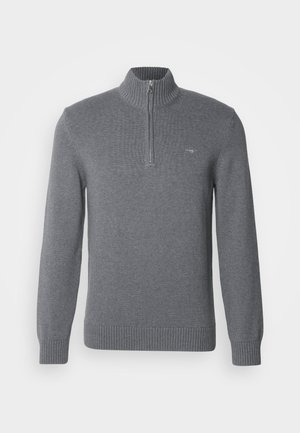 Grijze gebreide trui met een hoge kraag, half ritsdetail, lange mouwen en een geribde onderkant. Bevat een klein logo op de borst.