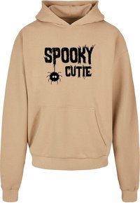 Beesidist tuunika, millel on eesmine tasku, musta tekstiga "SPOOKY CUTIE" ja väike ämblikugraafika. Valmistatud pehmest, tekstureeritud kangast.