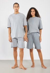 Šedá bavlnená oversized súprava tričiek a šortiek; voľný strih s jednoduchými švami a malým logom; mäkká textúra, ležérny dizajn.