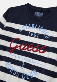 Pull rayé marine et blanc en tissu tricoté, avec un texte brodé rouge et bleu clair et un motif d'ancre sur le devant.