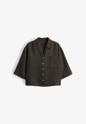 Chemise courte vert olive foncé à boutons, manches larges, col et poche poitrine côté gauche.