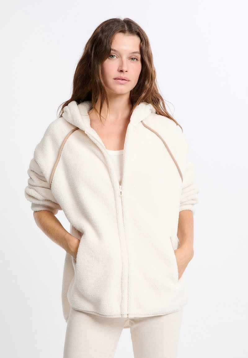 Felpa cremosa con zip e design semplice, tasche laterali e cappuccio, con un bordo beige a contrasto lungo le cuciture.