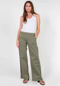 Pantalon large couleur vert olive en coton, doté d'une ceinture à la taille et de poches avant, associé à un débardeur blanc.