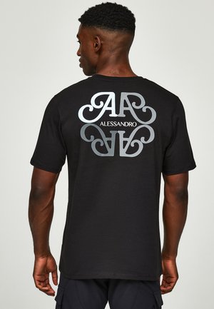 Mann mit dem Rücken zur Kamera trägt ein schwarzes T-Shirt mit großem weißem und grauem stilisiertem "AA" und "ALESSANDRO" Schriftzug auf dem Rücken.
