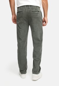 Gray corduroy pants with a straight-leg design. Features two back pockets and a textured surface. Paired with white shoes.