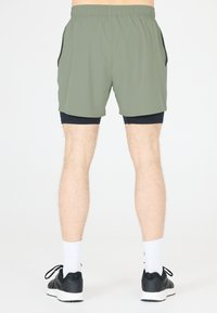 Herrsportshorts i olivgrön, tillverkade av lätt tyg, med resårmidja och sidofickor. Bärs över svarta kompressionsshorts.