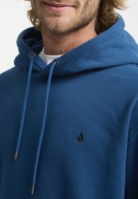 Blauwe hoodie van een katoenmix, met een trekkoordcapuchon, een gestructureerde afwerking en een klein zwart logo op de borst.
