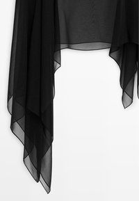 Gennemsigtigt sort stof med asymmetrisk spids kant og overlappende lag på hvid baggrund.