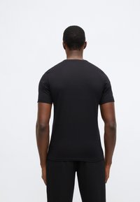 Černé tričko s krátkým rukávem a kulatým výstřihem. Hladká elastická látka; přiléhavý střih. Bez viditelných vzorů nebo kovových doplňků.