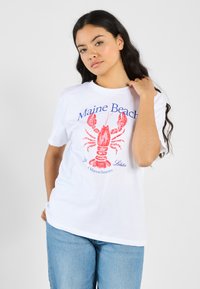 Hvid bomulds t-shirt med et rødt hummer grafik og blå tekst med teksten "Maine Beach" og "Lobster of Massachusetts." Klassisk pasform.