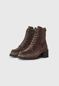 Botas de tornozelo em camurça castanha com atacadores, fecho lateral em zíper, painel de destaque texturizado e salto preto robusto; sola resistente com padrão de aderência.