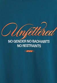Camiseta de algodón en color verde azulado con texto bordado en naranja: "Sin ataduras SIN GÉNERO SIN MALOS HÁBITOS SIN RESTRICCIONES (MWM)". Textura suave, diseño casual.