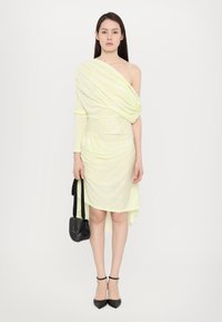 Rochie galbenă și albă cu dungi, off-the-shoulder, cu textură gathered, tiv asimetric, asociată cu o geantă neagră și tocuri.
