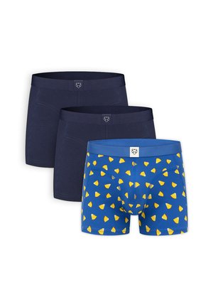 Tres calzoncillos tipo bóxer para hombre, dos en azul oscuro sólido y uno azul con un patrón de chips amarillos, todos con un pequeño logo blanco en la cintura.