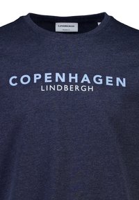 Mörkblå, avslappnad t-shirt med fet vit och ljusblå text: "KÖPENHAMN" ovanför "LINDBERGH" framtill. Kort ärm, rund hals.