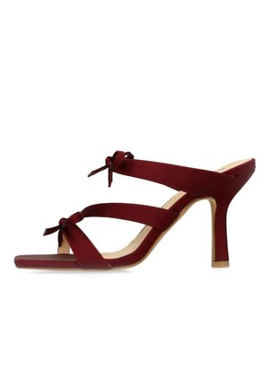 Red high-heeled mule sandal with two straps, each featuring a small bow detail, and a square toe design.