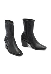 Czarne skórzane botki za kostkę z ostrym noskiem, zamek błyskawiczny i wysoka, blokowa pięta. Faktura jest gładka z delikatnym wzorem słojów.
