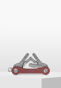 Multiverktyg med ett rödtexturerat handtag och verktyg i rostfritt stål, med olika blad och redskap, kompakt design.