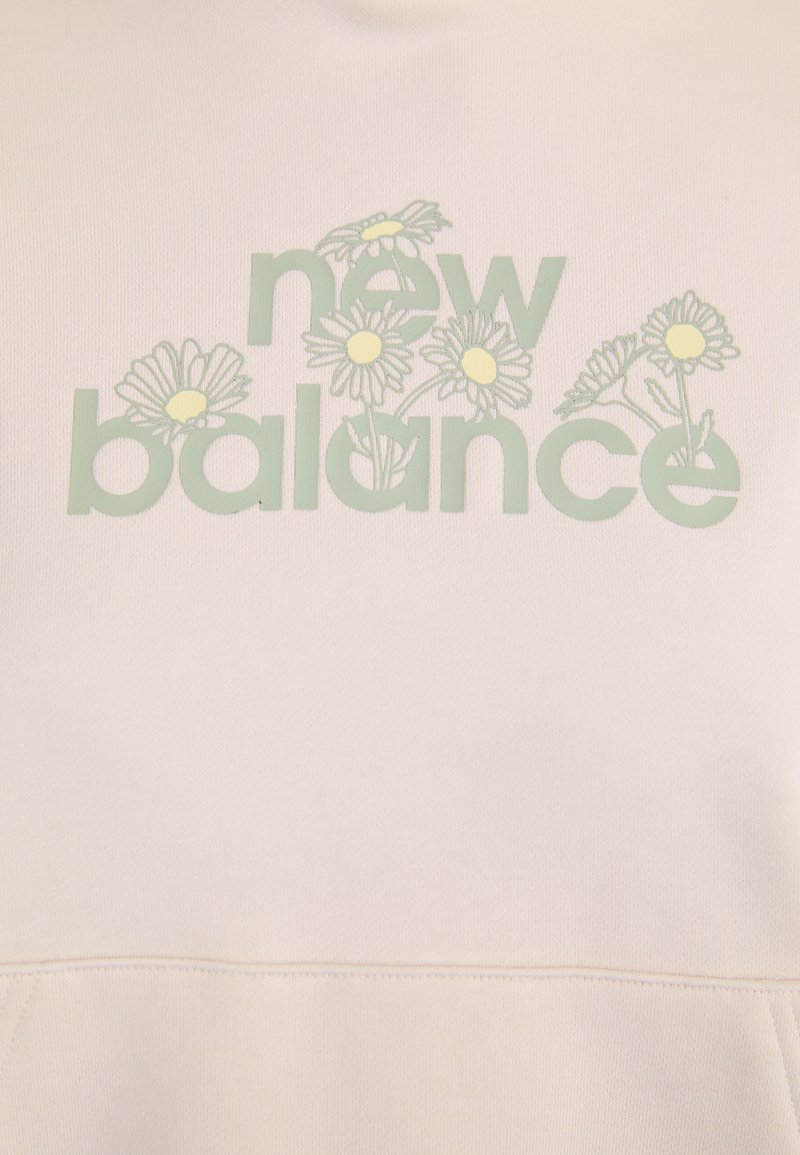 Helles, pinkes Sweatshirt mit grünem "New Balance"-Schriftzug und weißen Gänseblümchen als Akzenten, glatte Textur und lässiges Design.