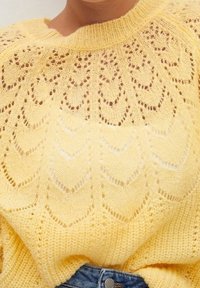 Żółty sweter z dzianiny z falbaniastym wzorem koronkowym i ściągaczem w dekolcie. Miękka faktura z otwartymi ściegami, tworząca lekki wzór.