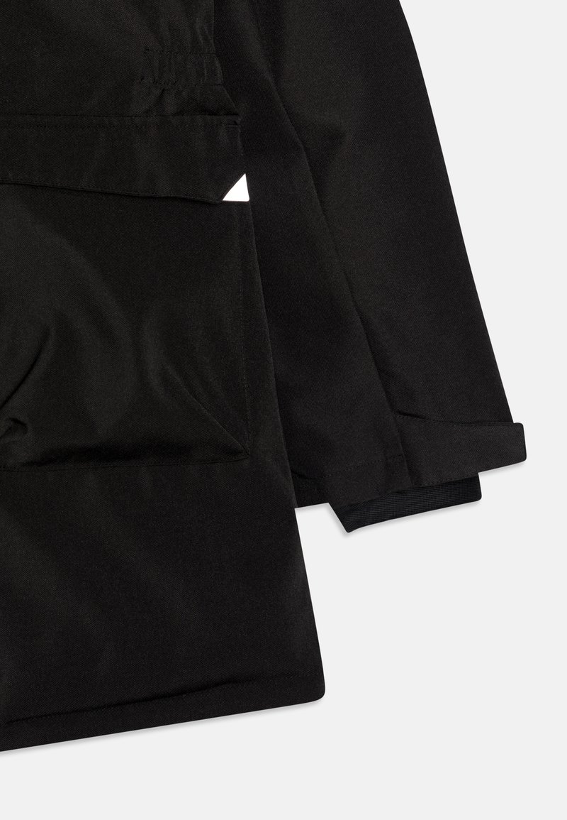 Veste noire en tissu texturé, avec une poche avant et des poignets avec un ourlet élastique noir. Design épuré et angulaire avec des accents minimalistes.