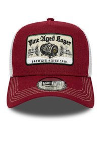 Rote Baseballmütze mit weißem Netzmaterial auf der Rückseite, auf der Vorderseite mit einem gestickten Patch eines Fasses und dem Text "Pine Aged Lager" versehen. Verstellbarer Riemen.