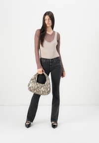 Beige top tank ker layering under brown long-sleeve top, jeans hitam, dan sepatu hitam mengkilap. Membawa tas tangan dengan cetakan ular yang berbentuk tekstur.