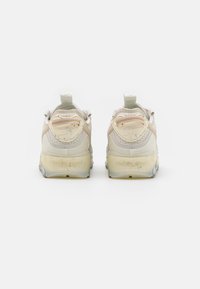 Baskets beige clair avec une tige en maille texturée, des accents moulés et une semelle translucide avec des éclats. Comprend une languette au talon.