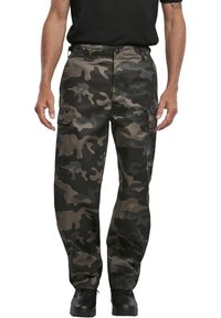 Cargo byxor i mörkgrön och svart camouflage-mönster, med flera fickor, avslappnad passform och kraftig tygtextur.