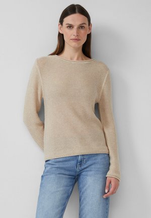 Beige strukturierter Strickpullover mit weitem Ausschnitt und langen Ärmeln, kombiniert mit hellblauen Jeans. Der Stoff hat ein leicht offenes Gewebe.