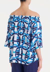 Top off-the-shoulder in tessuto intrecciato. Caratterizzato da un motivo geometrico blu e navy, scollatura elastica e maniche a campana.