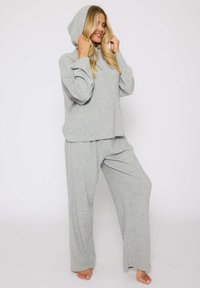 Conjunto de ropa de casa en gris claro, hecho de tela suave, que incluye una parte superior con capucha y pantalones holgados con cintura elástica, de acabado texturizado.
