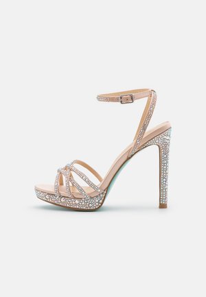 Nøgen højhælet sandal med ankelrem, der har flere krydsede remme, rhinestones og en glitrende platform.