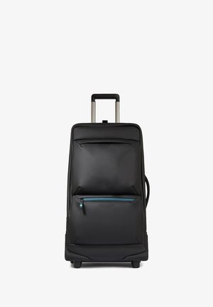 Maleta negra con ruedas y superficie texturizada, un bolsillo frontal con cremallera y acento en color verde azulado, y un mango metálico retráctil.