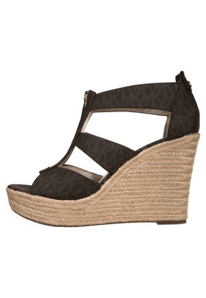 Sandale compensée noire avec talon plateforme en jute tressé, bout ouvert, design à bride en T, et fermeture éclair sur la partie supérieure.
