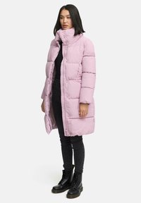 Padded pink coat with high collar, snap and zip closure. Fabric appears shiny, featuring a quilted design. Worn over black outfit.