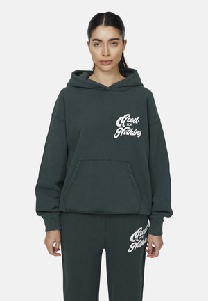Hoodie vert foncé avec une poche avant, comportant le texte blanc "Good for Nothing". Assorti avec un pantalon identique, affichant également le même texte.