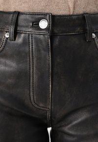 Shorts negri din piele cu un design cu cinci buzunare, cusături vizibile și un sistem de închidere cu un nasture metalic la talie. Finisaj mat texturat.