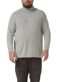 Szary golf z materiału o teksturowanym splocie, z długimi rękawami oraz prążkowanym kołnierzem i dolnym wykończeniem. Noszony na ciemnych spodniach.
