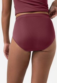 Burgundy högmidjade shorts med en slät textur, med en enkel design och sydda detaljer. Bakifrån är de sömlöst skurna.